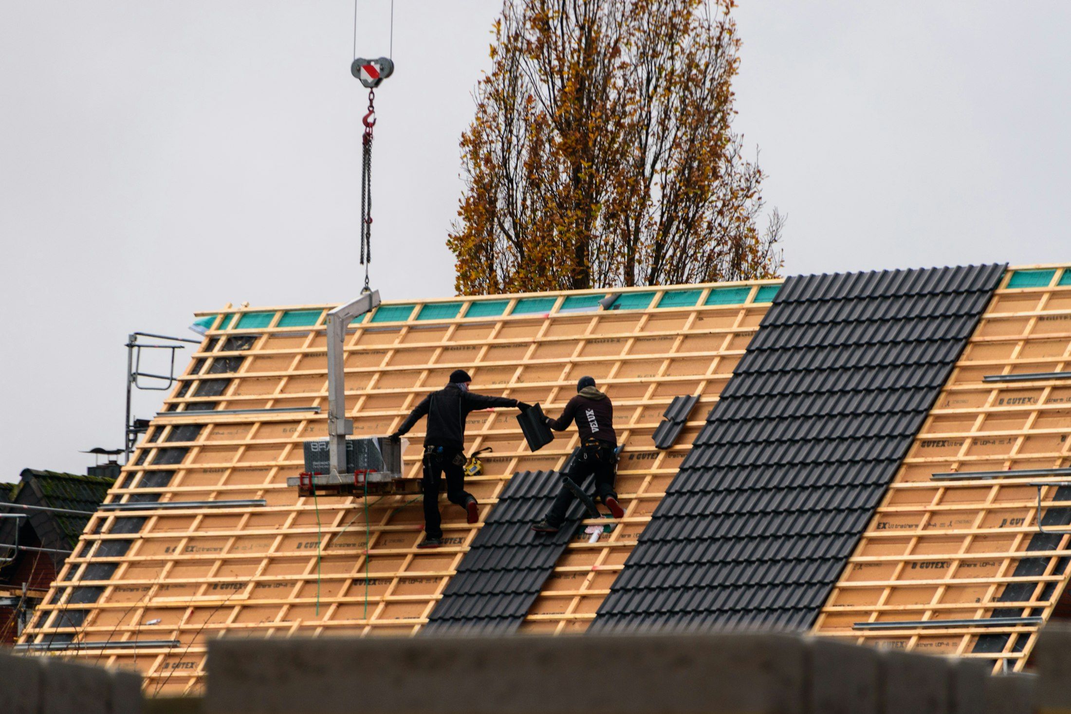 Roofers laying new roof tiles on a pitched roof A. Dawson Roofing Services Fife